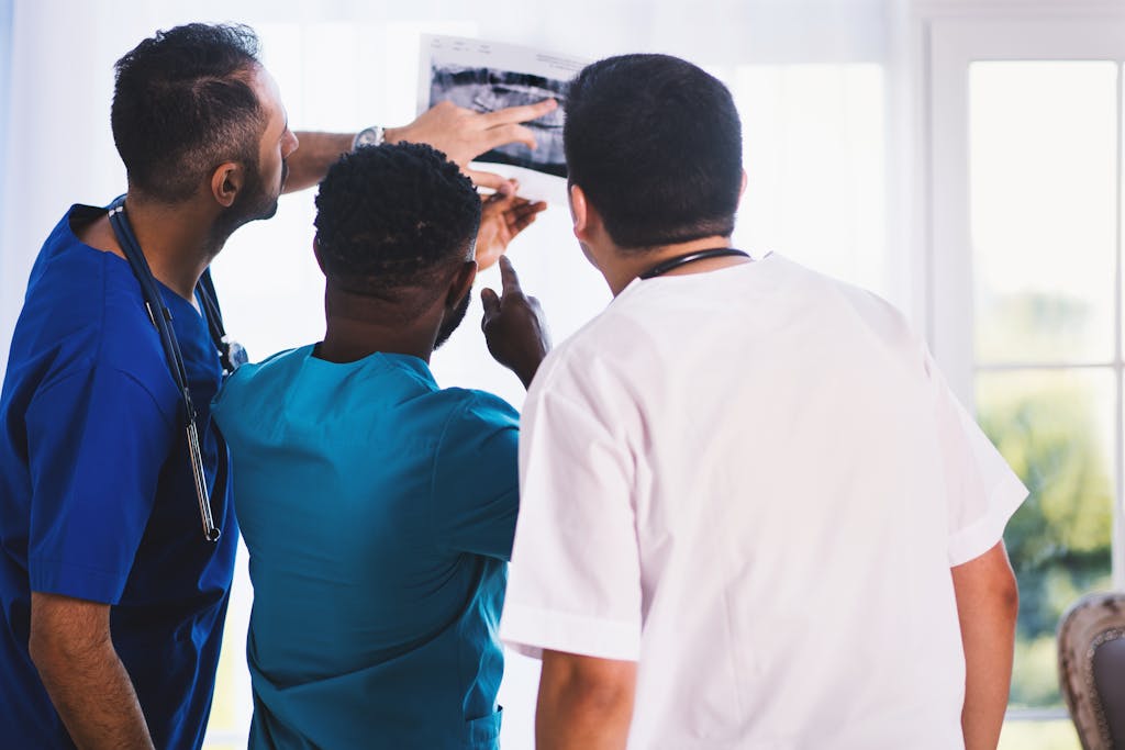 Doctors collaboratively analyzing an X-ray in a clinical setting, showcasing teamwork and medical expertise.